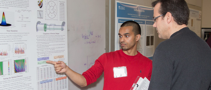 Student presenter Abhilash Matthews (left) describes his research to judge Prof. Colin Denniston (right).